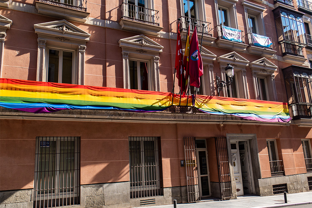 Madryt, długa tęczowa flaga na oświetlonym słońcem balkonie