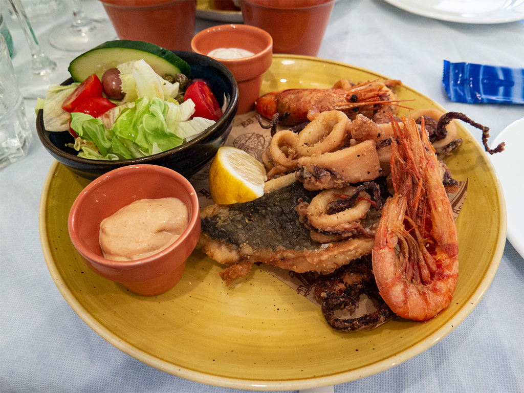 Obiad na talerzu: smażone ryby, krewetki i kalmary oraz sałatka i sos