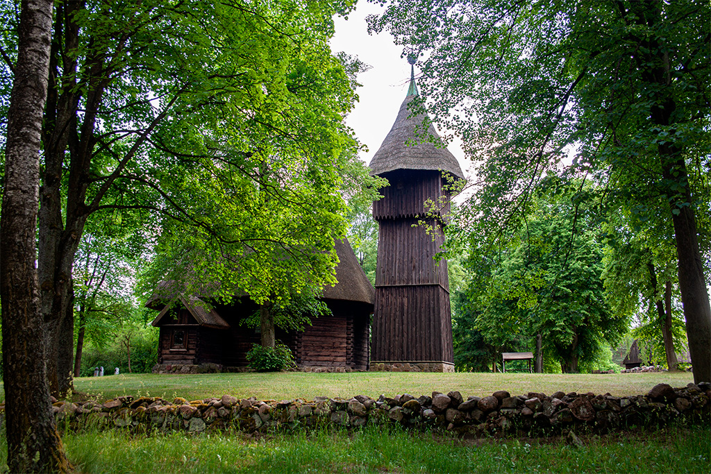 Skansen Olsztynek –  drewniana dzwonnica wśród drzew