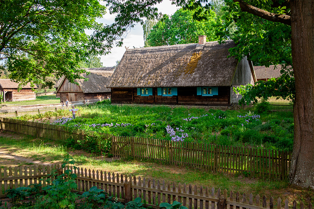 Skansen Olsztynek – chaty, a przed nimi ogródek